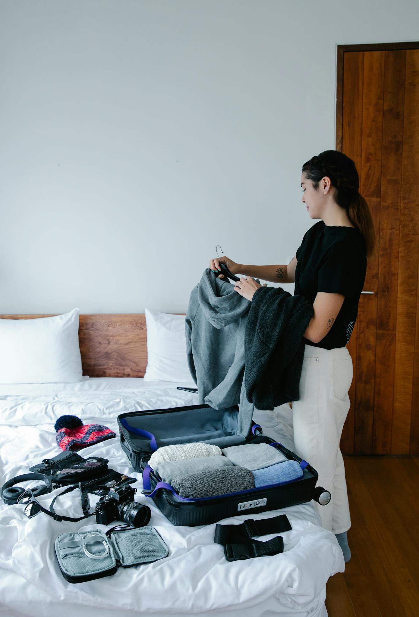 Woman packing clothes into suitcase on bed, preparing for travel.
